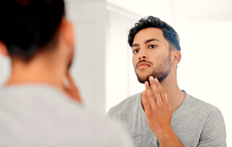 Man looking at his complexion in the bathroom mirror