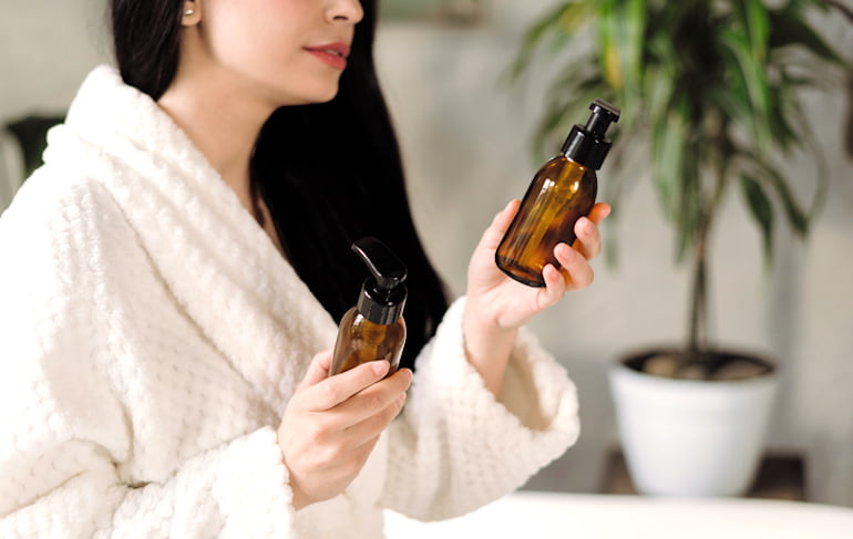 Woman at spa holding two products with Skincare sustainable packaging in glass