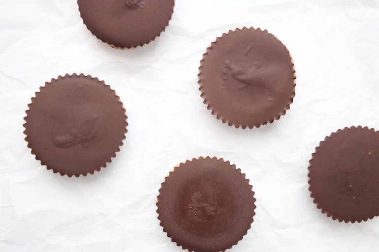 Overhead shot of dark chocolate almond butter cups neatly arranged on a kitchen counter